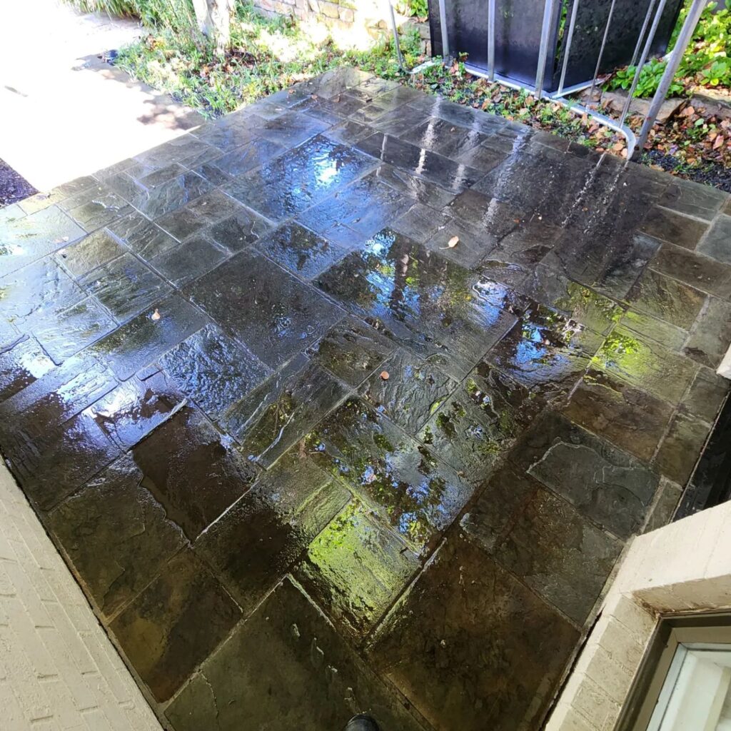 A patio with water on the ground and leaves